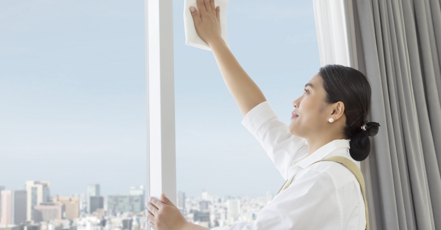 Housekeeper wiping windows